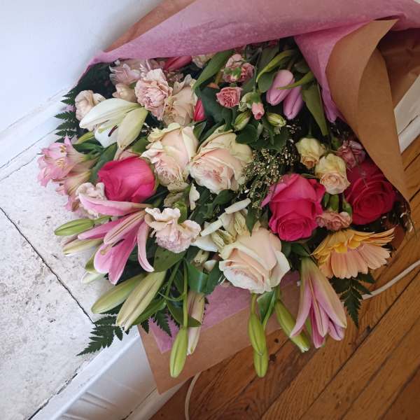 Bouquet of pink and cream roses with lilies wrapped in brown and pink paper