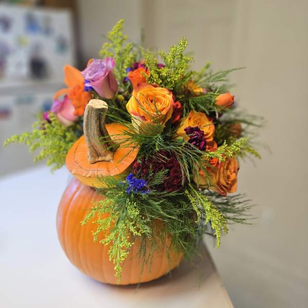 Pumpkin-shaped floral arrangement with orange and purple roses