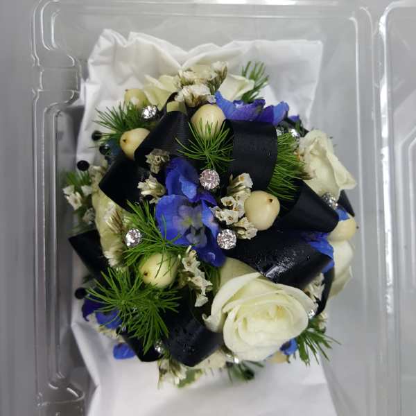 Small bouquet with white and blue flowers in a clear plastic box