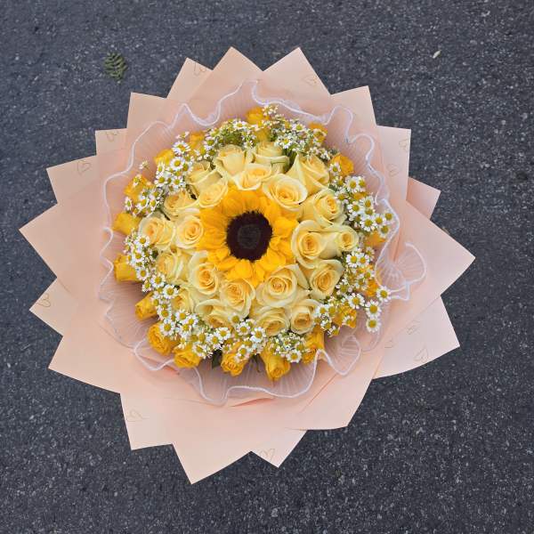 Yellow roses and a sunflower bouquet wrapped in pale pink paper