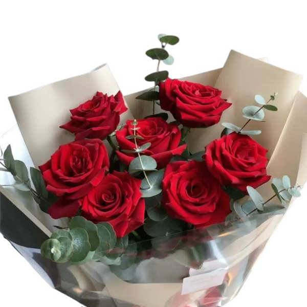 Bouquet of red roses wrapped in cream paper with eucalyptus