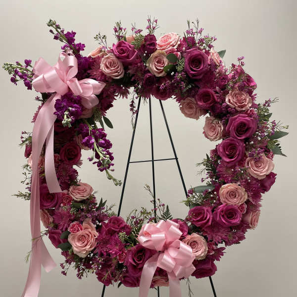 Heart-shaped floral wreath of pink and magenta roses with ribbon bows