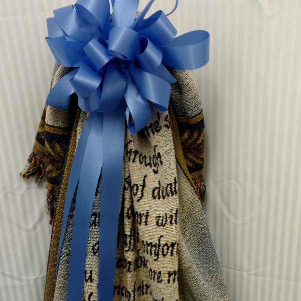 Decorative woven blanket with a large blue ribbon bow