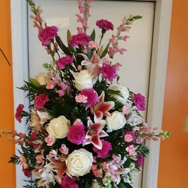 Standing floral spray with pink and white flowers on a black easel
