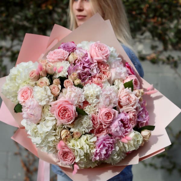 Large bouquet of pink and white roses and hydrangeas wrapped in blush paper