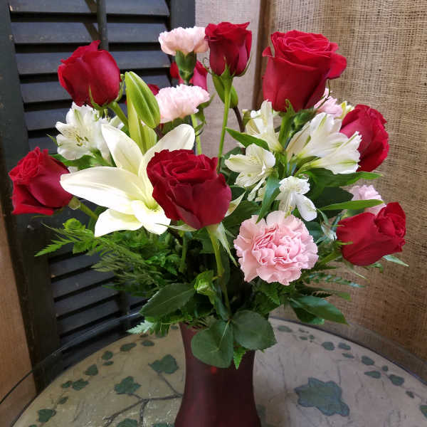 Bouquet of red roses, white lilies, and pink carnations in a vase