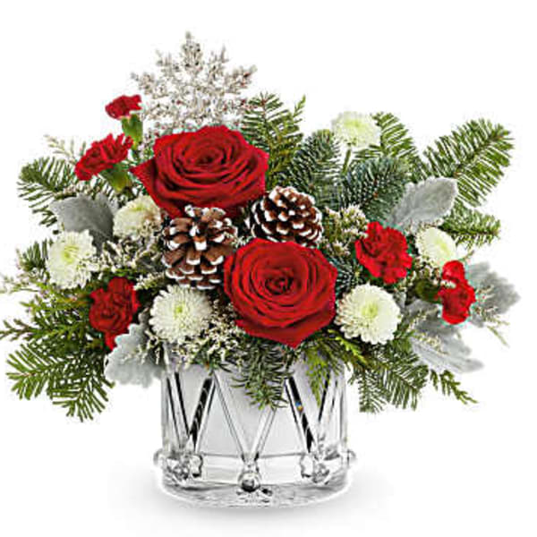 Red roses and white flowers in a clear glass vase with pinecones