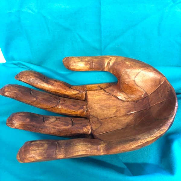 Wooden hand sculpture on a bright blue cloth background