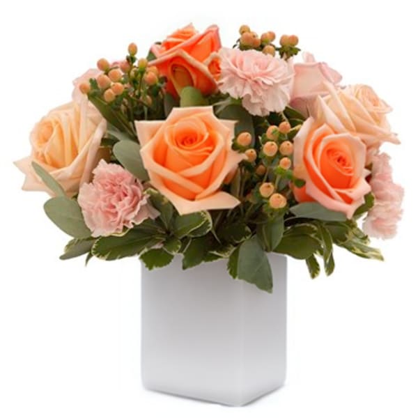 Peach roses and pink carnations in a white vase