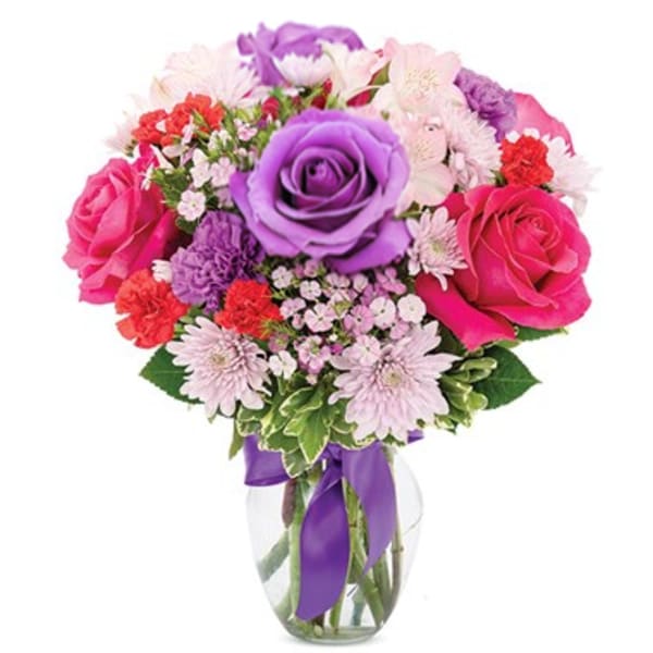 Bouquet of pink and purple flowers in a glass vase with a purple ribbon