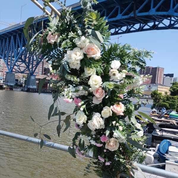 Tall floral arrangement with white and blush roses by a river