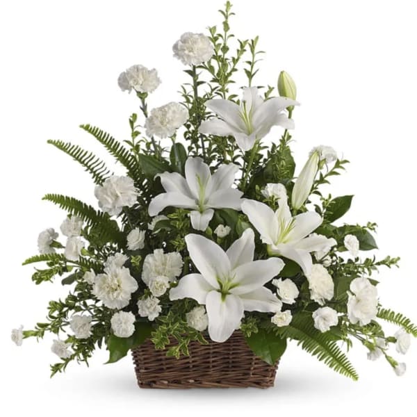 White lilies and carnations arranged in a brown wicker basket