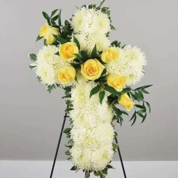 White floral cross with yellow roses on a stand