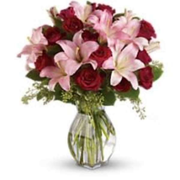 Bouquet of pink lilies and red roses in a clear glass vase