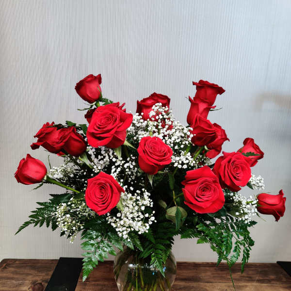 Red roses arranged in a clear glass vase with baby's breath