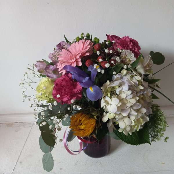 Mixed bouquet in a dark vase with pink, white, purple, and yellow flowers