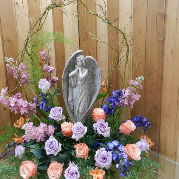 Floral arrangement with a gray angel statue and pastel roses