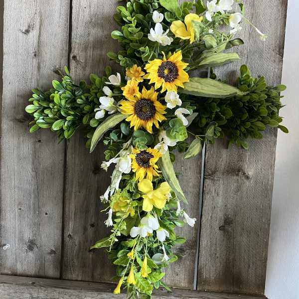 Cross-shaped floral arrangement with yellow sunflowers and white blossoms