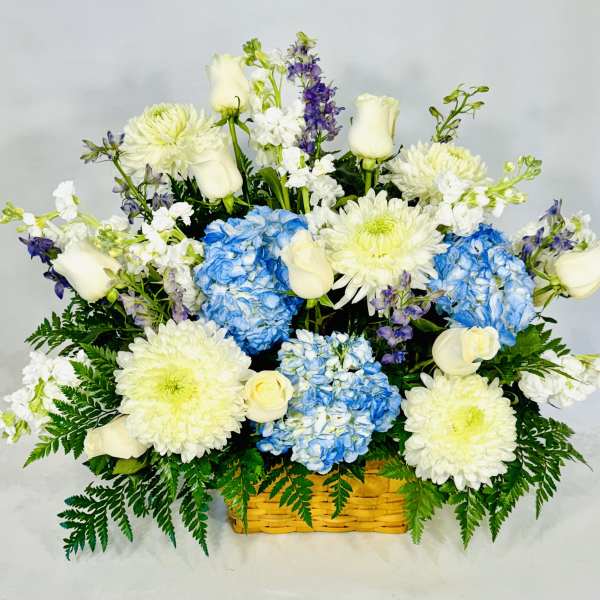 Basket arrangement of white roses, blue hydrangeas, and white chrysanthemums