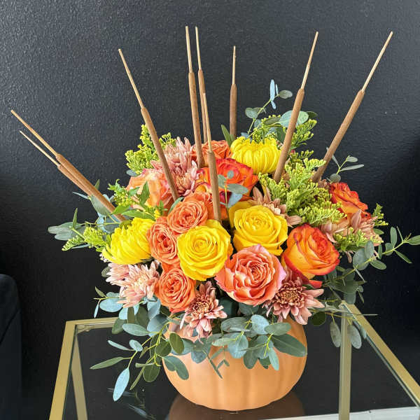 Orange and yellow floral arrangement in a pumpkin-shaped container