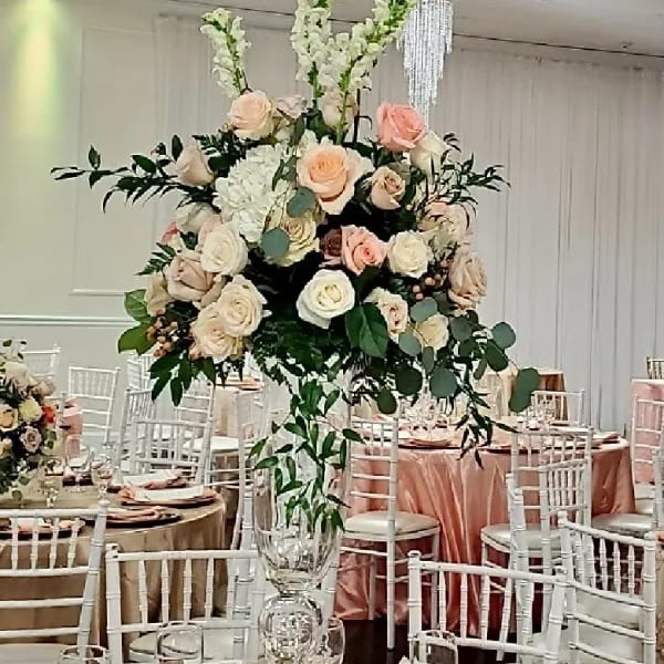 Tall floral centerpiece with blush and white roses in a clear vase