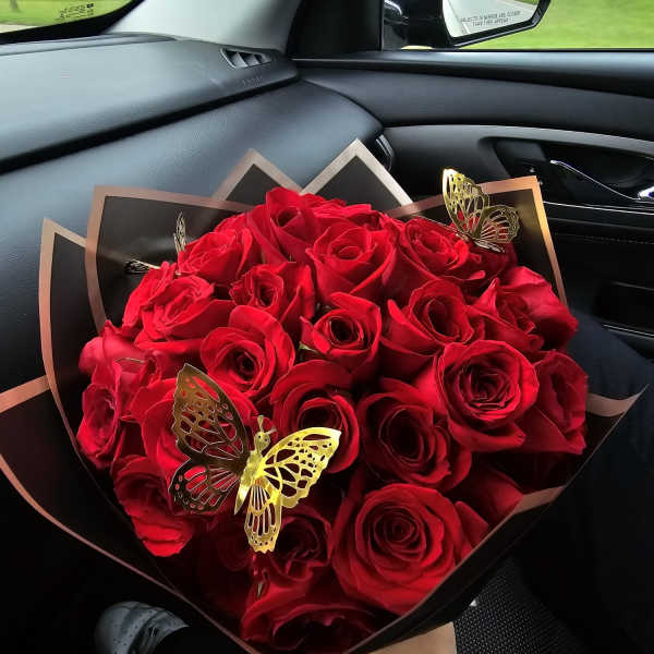Bouquet of red roses wrapped in black paper with butterfly accents