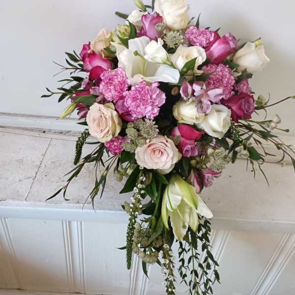 Hand-tied bouquet of pink and white roses with trailing greenery