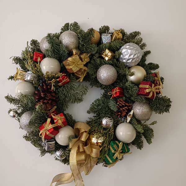 Christmas wreath with ornaments, gift boxes, and gold ribbon