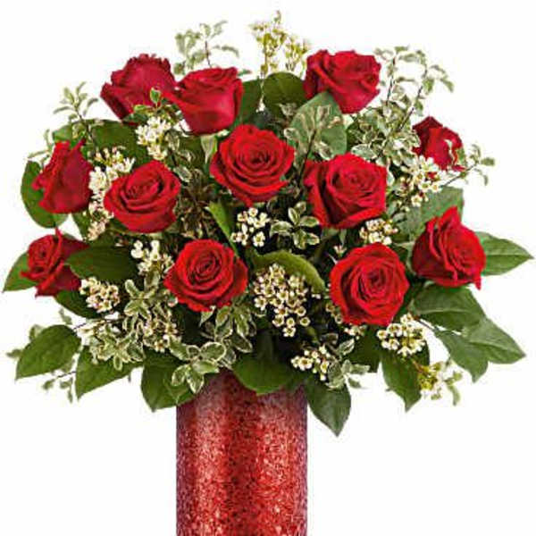 Red roses arranged in a red vase with white filler flowers