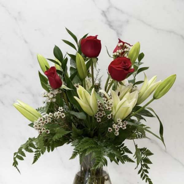 Red roses and white lilies in a clear glass vase
