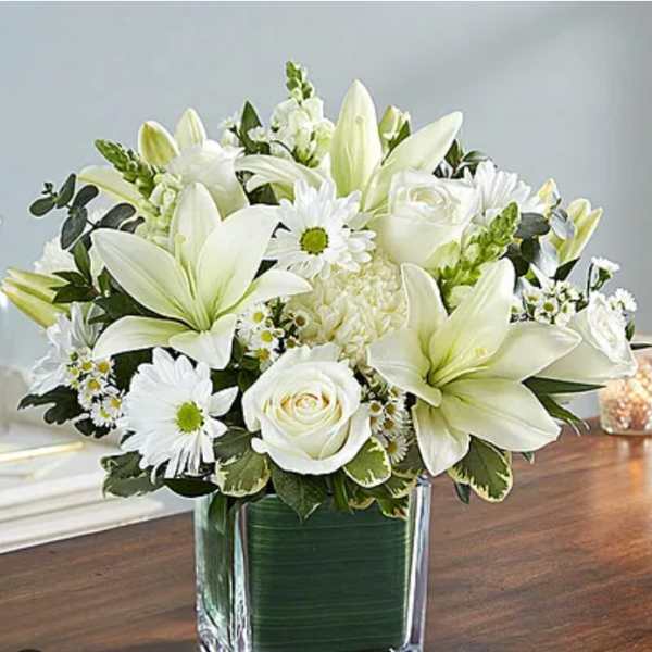 White lilies and roses arranged in a clear glass vase