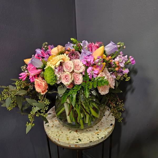 Mixed pink, peach, and lavender flowers arranged in a glass vase