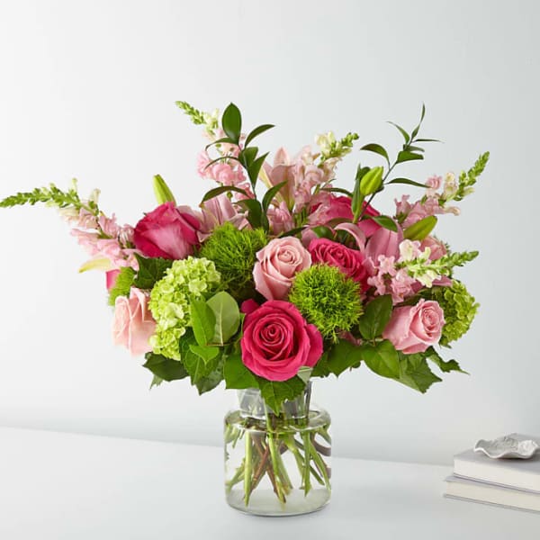 Pink roses and lilies arranged in a clear glass vase