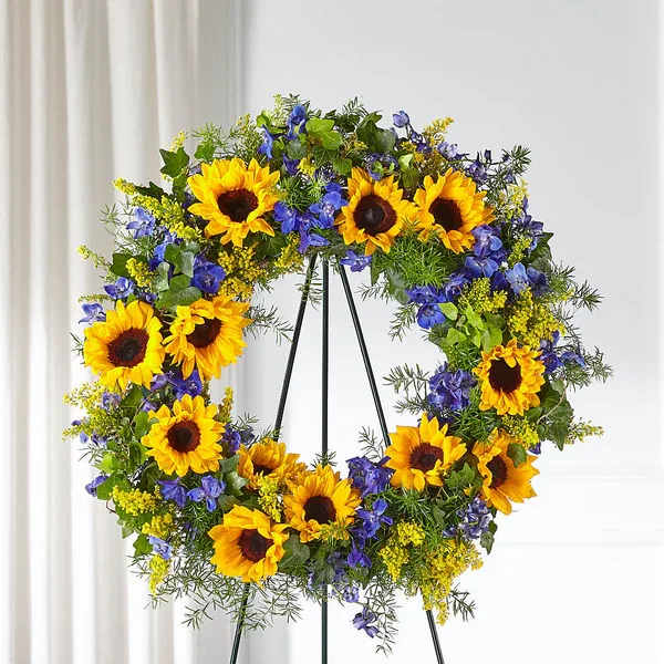 Sunflower wreath with blue and yellow flowers on a black stand