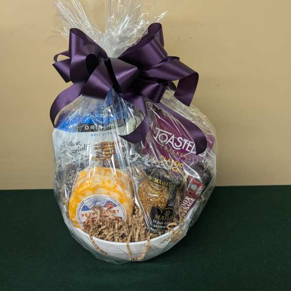 Gift basket with assorted snacks wrapped in clear cellophane and a purple bow