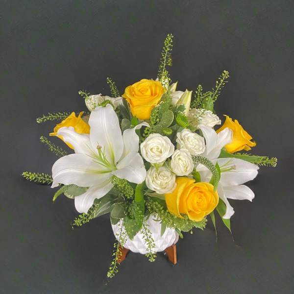 White lilies and yellow roses arranged in a white vase