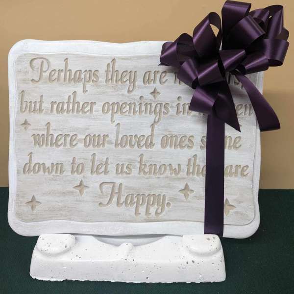 White memorial plaque with a purple ribbon bow on a stand