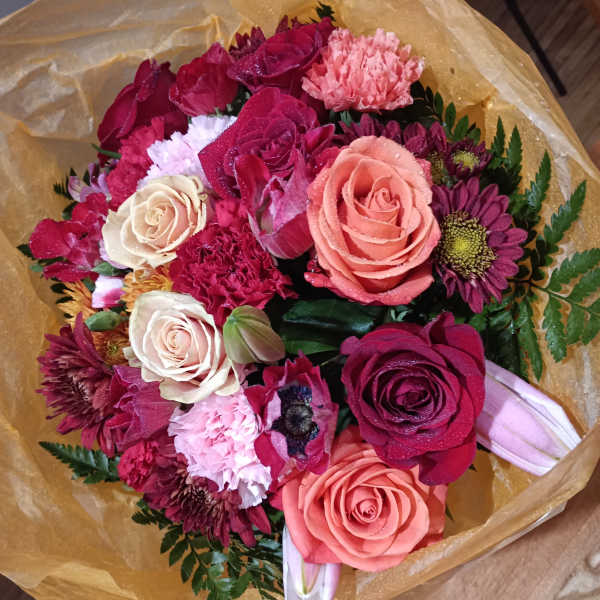 Bouquet of pink and burgundy roses with carnations and daisies in gold wrap