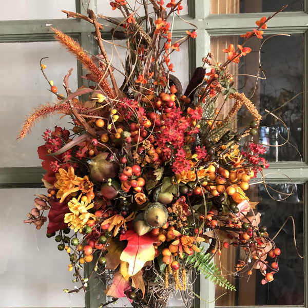 Autumn floral arrangement with orange blooms and berries on a door