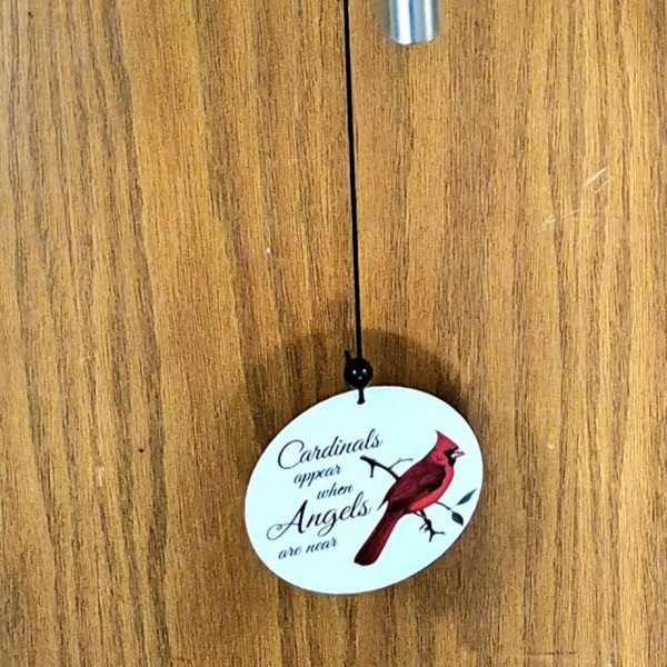 Cardinal-themed metal wind chime hanging on a wooden door