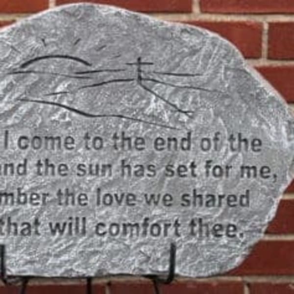 A painted memorial stone with a quote on a brick wall