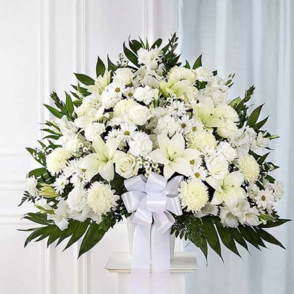 White floral spray with a ribbon on a stand