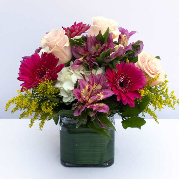 Mixed bouquet of pink and white flowers in a square glass vase