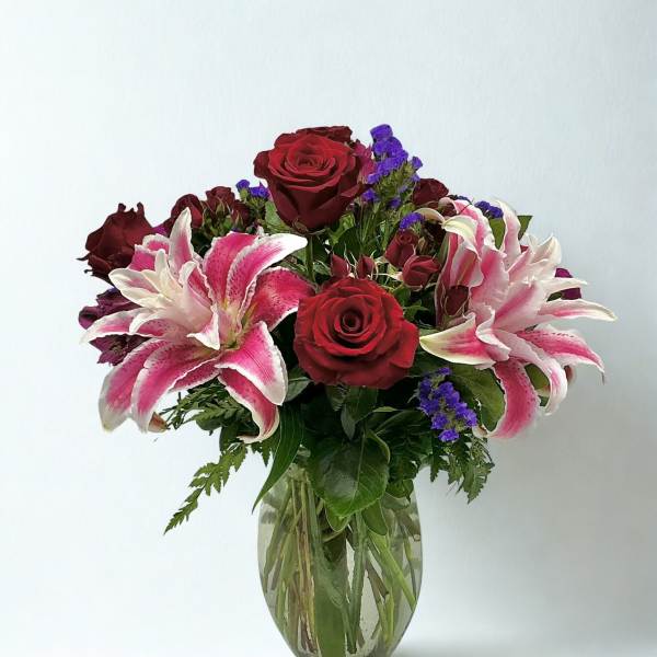 Bouquet of red roses and pink lilies in a clear glass vase