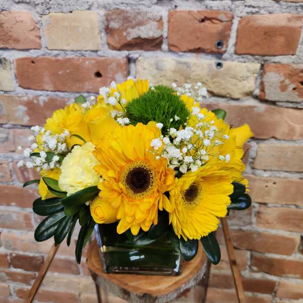 Yellow flower arrangement in a square glass vase