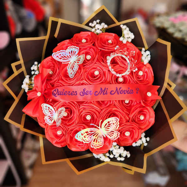Red rose bouquet with butterflies and a ribbon reading "Quieres Ser Mi Novia?"