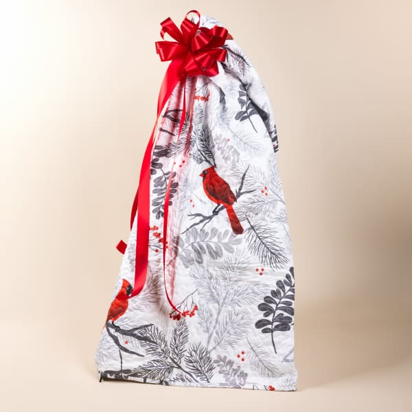 Gift bag wrapped in bird-patterned fabric with a red ribbon bow