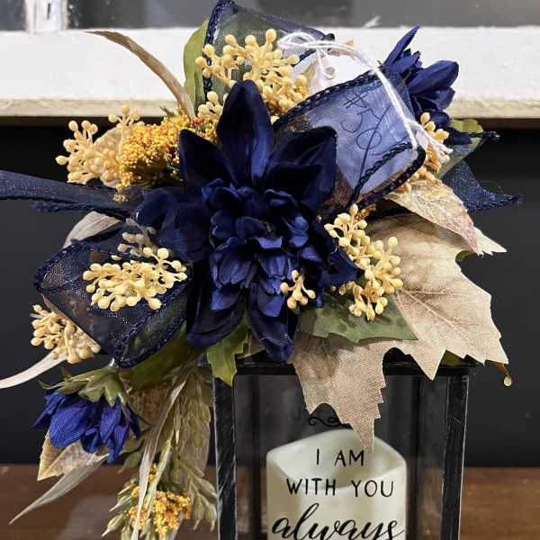 Silk floral arrangement in a black lantern with a memorial candle