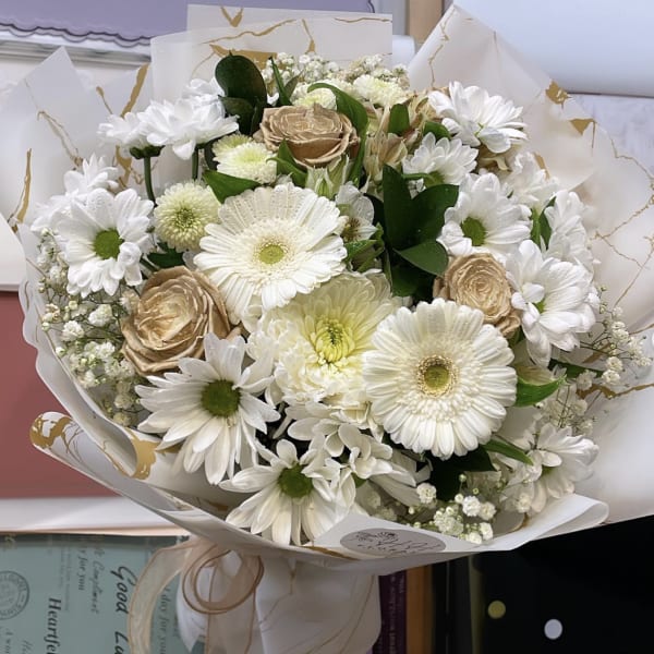Bouquet of white daisies and beige roses wrapped in white paper