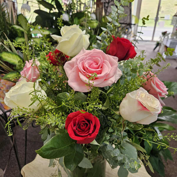 Arrangement of pink, red, and white roses in a clear glass vase
